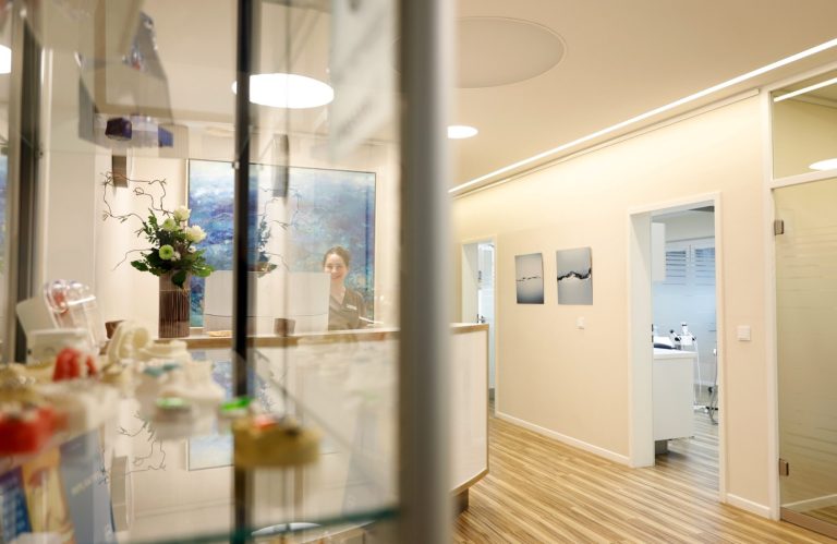 Heller Innenraum mit Empfangstresen und Flur zu weiteren Räumen.