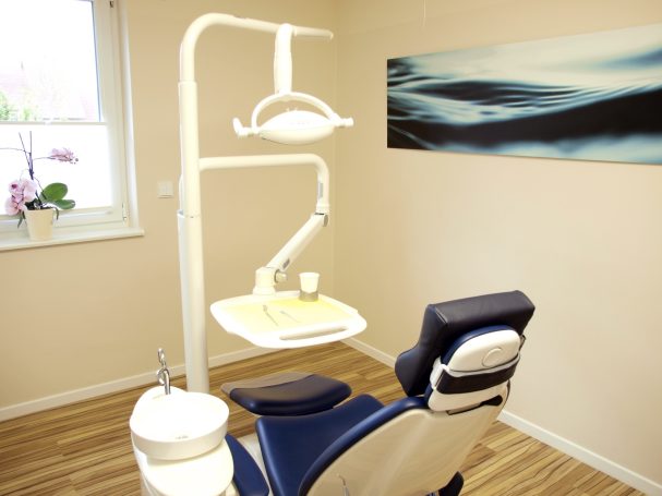 Zahnarztpraxis mit einem Behandlungsstuhl und moderner Ausstattung in einem hellen Raum.